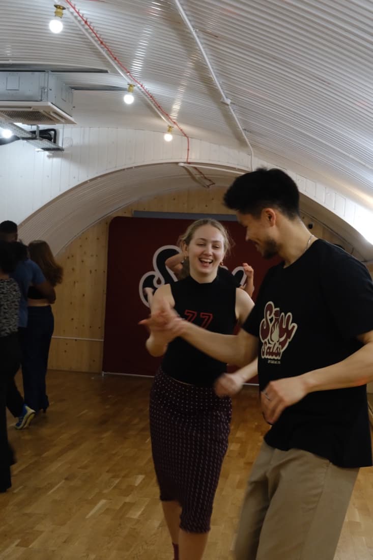 Two Soy Salsa students laughing mid-dance in London